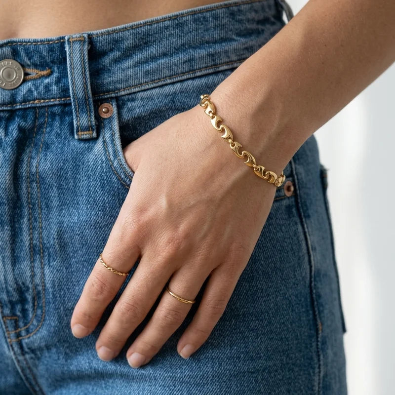 A close-up of an 18ct gold plated chunky puffy wave link bracelet with lobster clasp worn on a wrist 