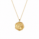 A gold pendant necklace featuring a textured, circular wax seal design with an embossed sun motif, suspended from a delicate gold chain against a solid white background.