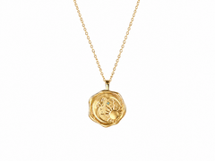 A gold pendant necklace featuring a textured, circular wax seal design with an embossed sun motif, suspended from a delicate gold chain against a solid white background.